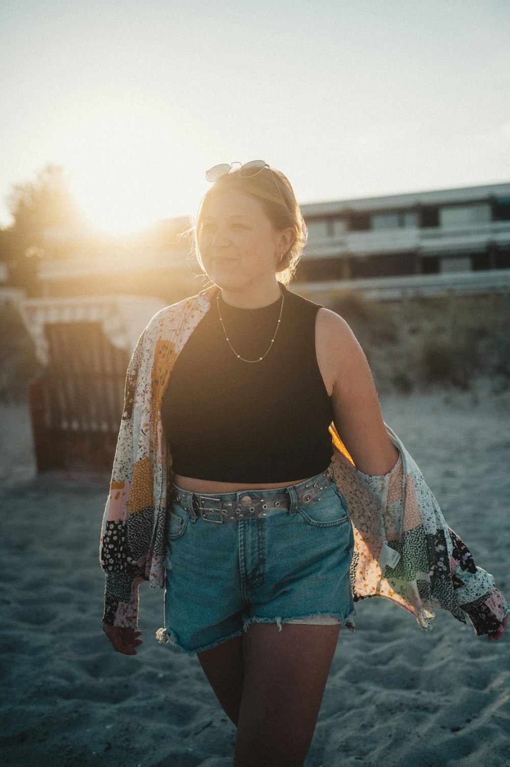 a woman walking on the beach at sunset