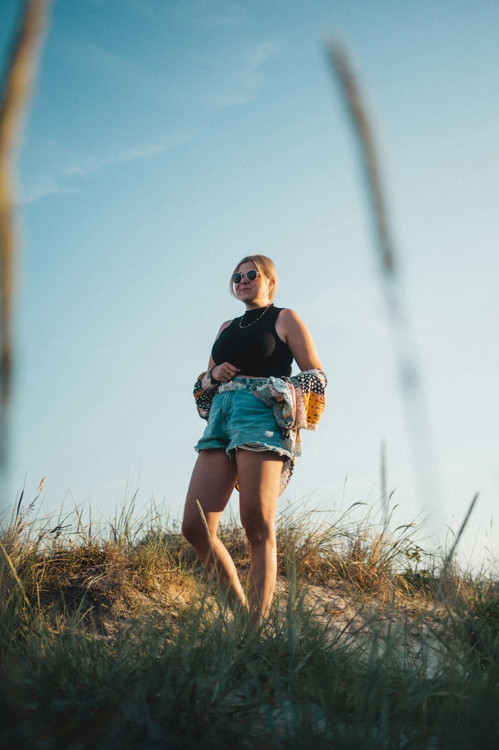 a woman standing on top of a grass covered hillside