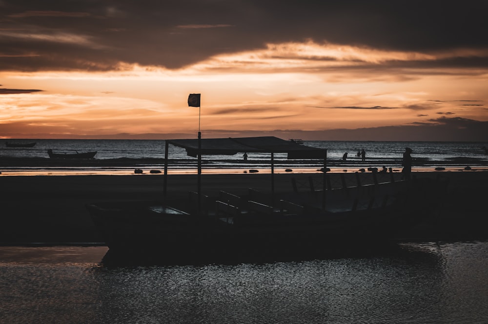 a boat sitting on top of a beach under a cloudy sky