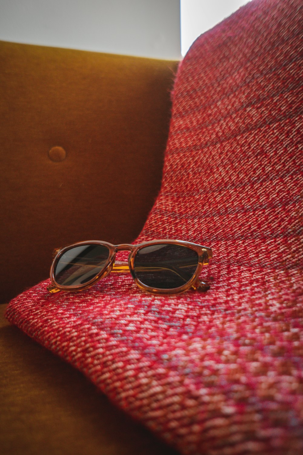 a pair of sunglasses sitting on top of a red blanket