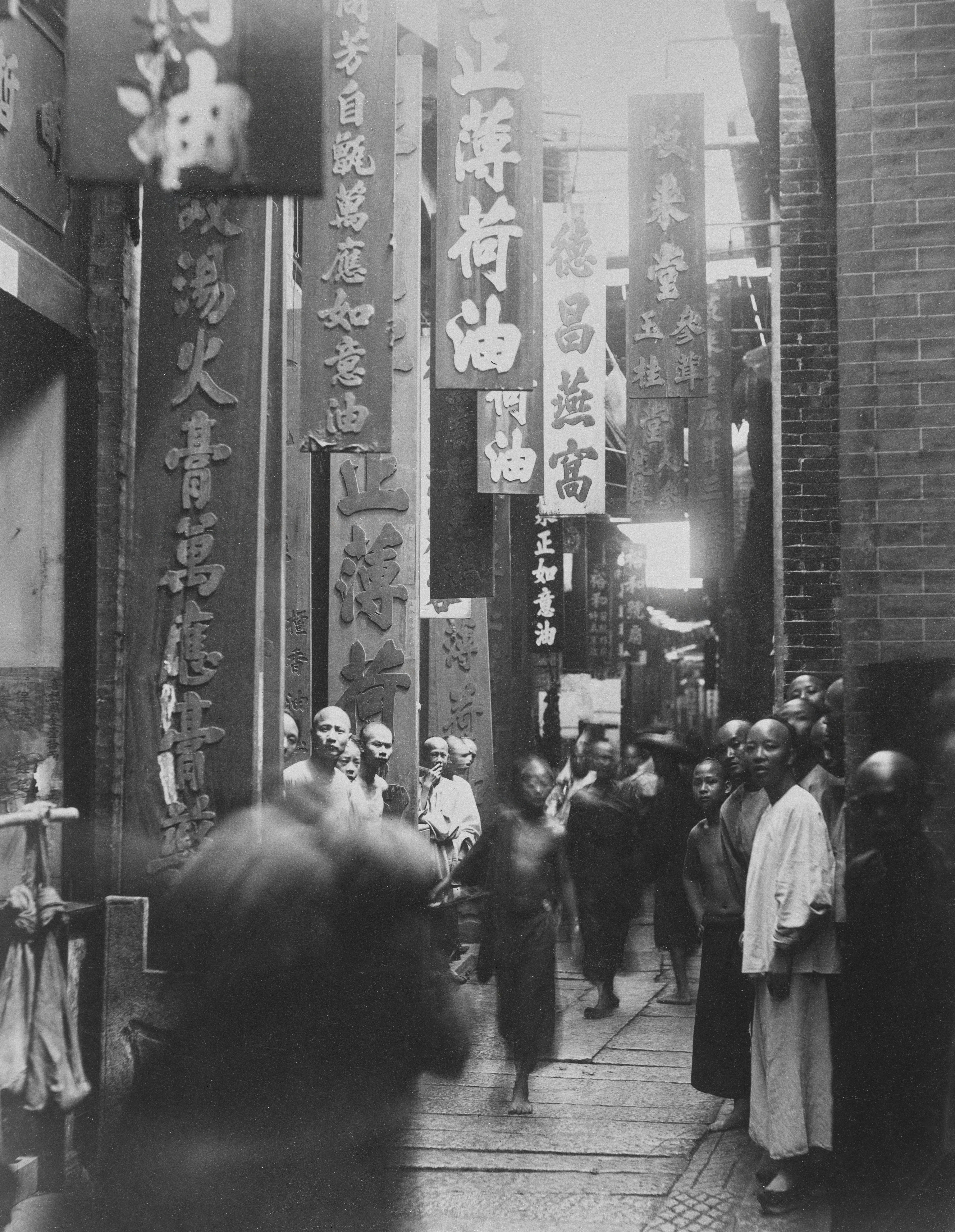 a group of people walking down a street next to tall buildings