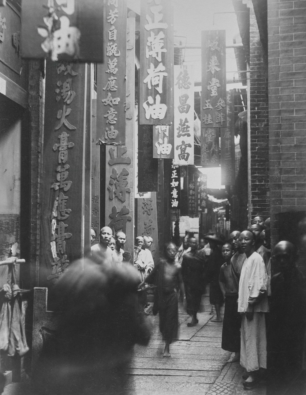 a group of people walking down a street next to tall buildings