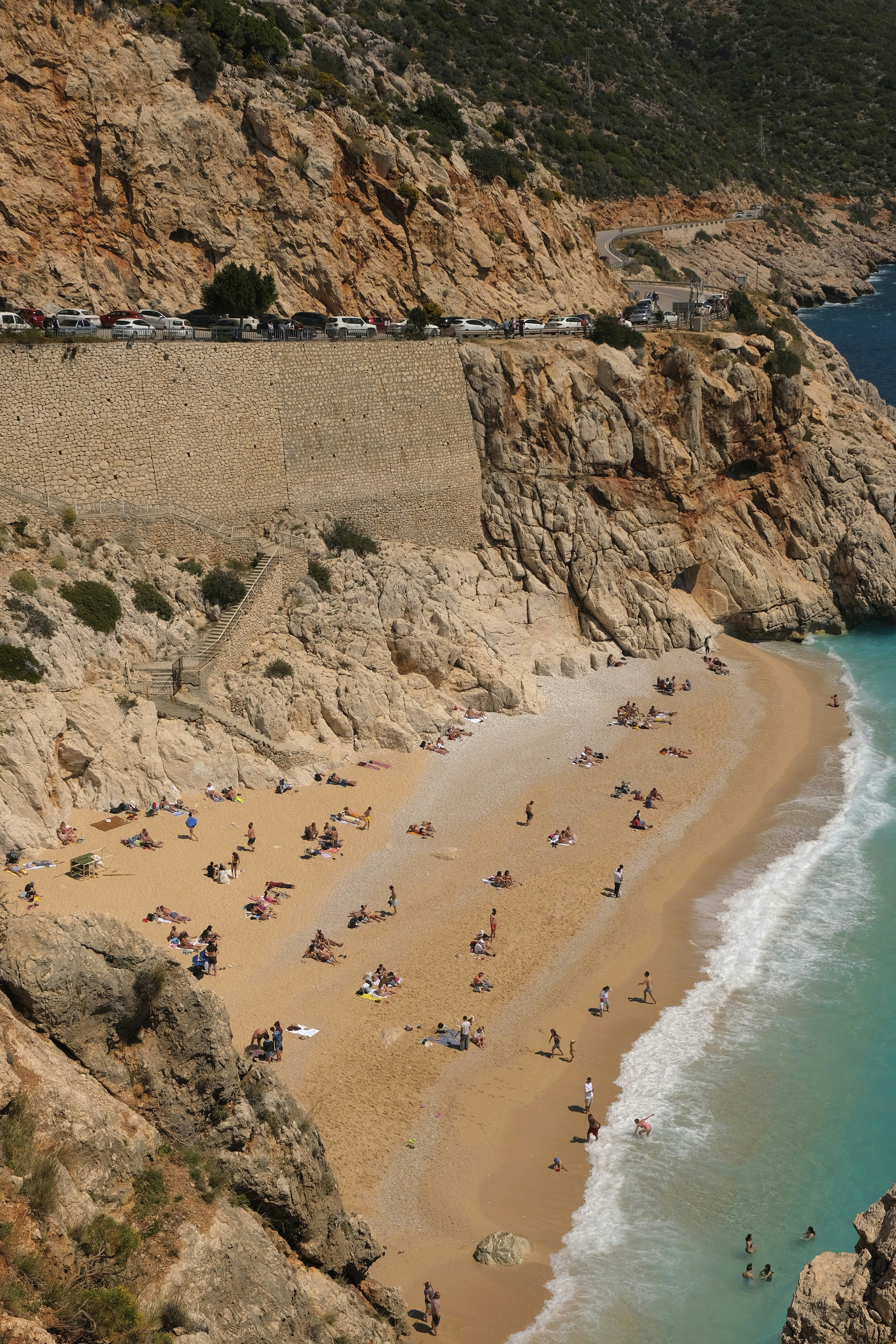 Turquoise sea and beach beneath steep coastal cliffs