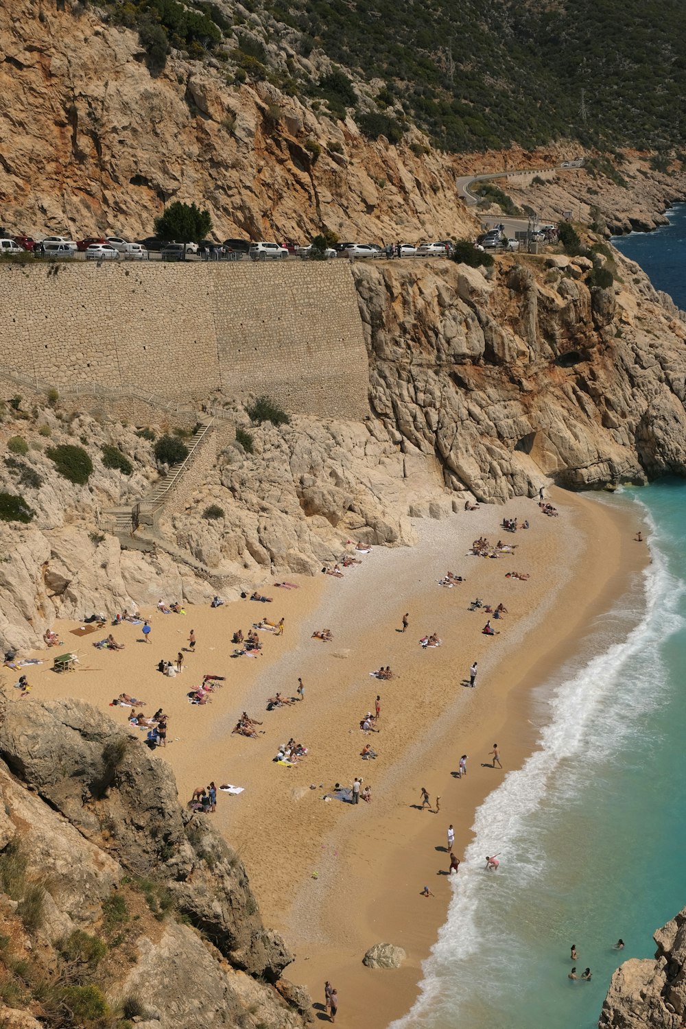 a group of people on a beach next to a cliff