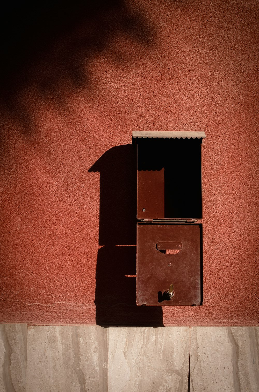 the shadow of a wall mounted mailbox on the side of a building