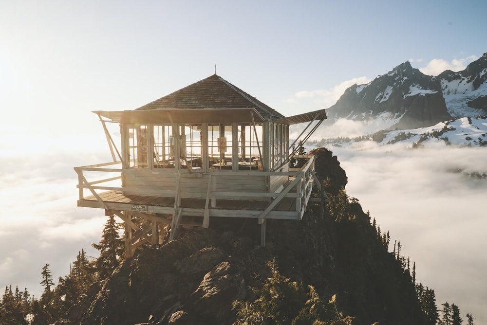a wooden structure on top of a mountain surrounded by clouds