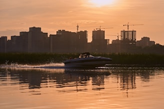 A vibrant speedboat cutting through the sparkling waters of the New York Harbor with the city skyline glowing at sunset.