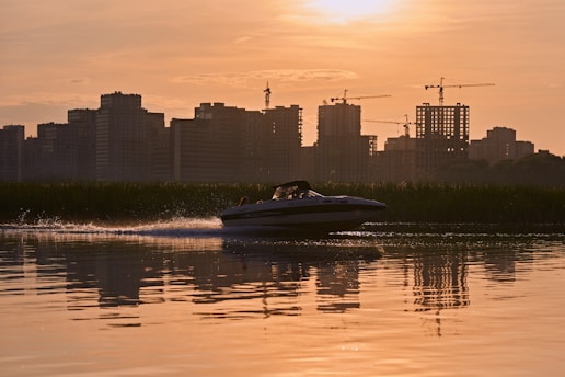 A vibrant speedboat cutting through the sparkling waters of the New York Harbor with the city skyline glowing at sunset.