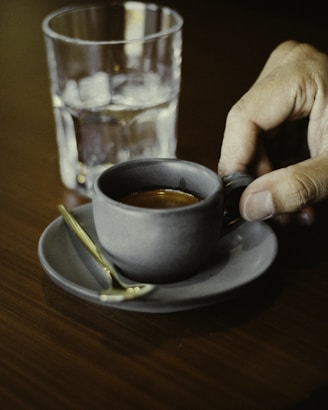 a person is holding a spoon over a cup of coffee