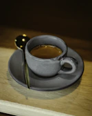 A steaming cup of freshly brewed espresso served on a rustic wooden table bathed in morning light.