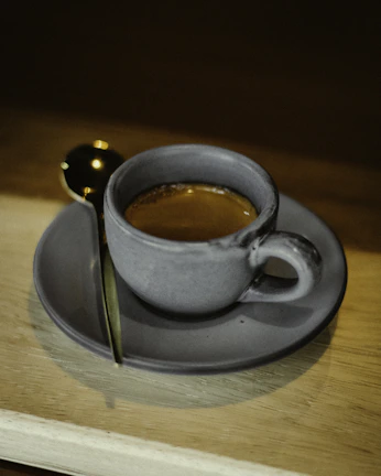 A steaming cup of freshly brewed espresso served on a rustic wooden table bathed in morning light.