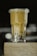 A tall glass of milk tea with black tapioca pearls settled at the bottom, placed on a wooden surface. The drink is creamy with a smooth texture, and the background is blurred with soft lighting.