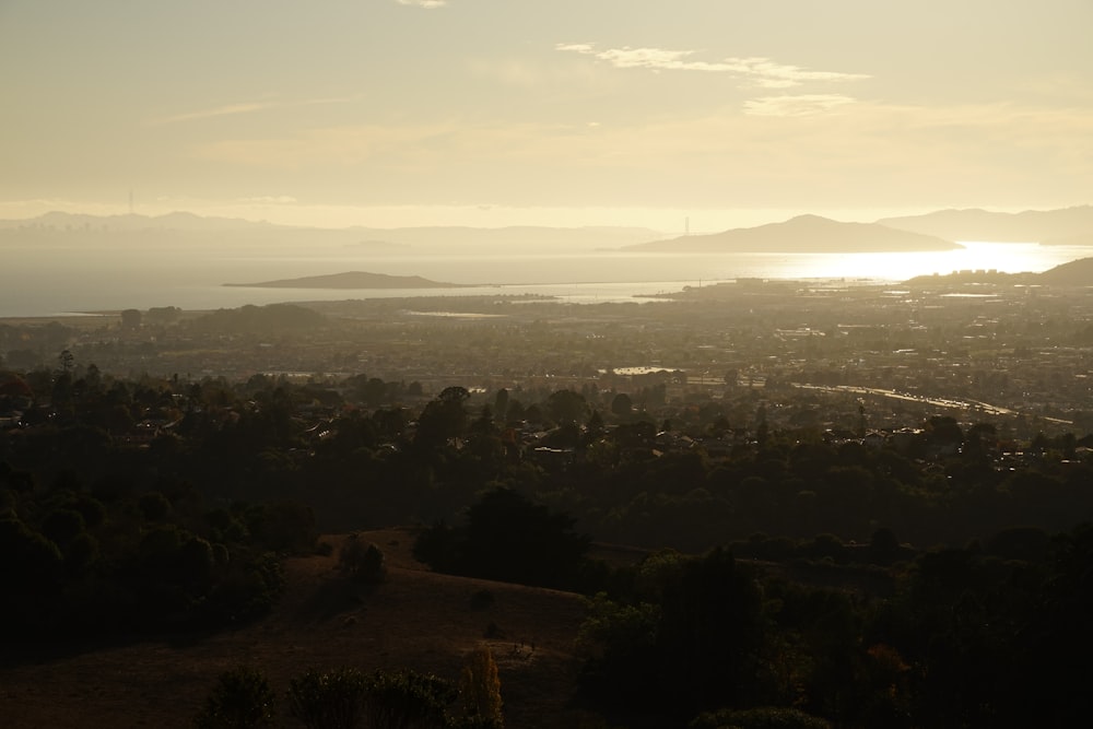 the sun is setting over a city with mountains in the background