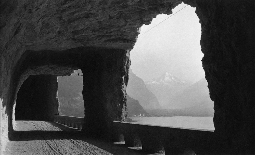 a black and white photo of a tunnel with mountains in the background