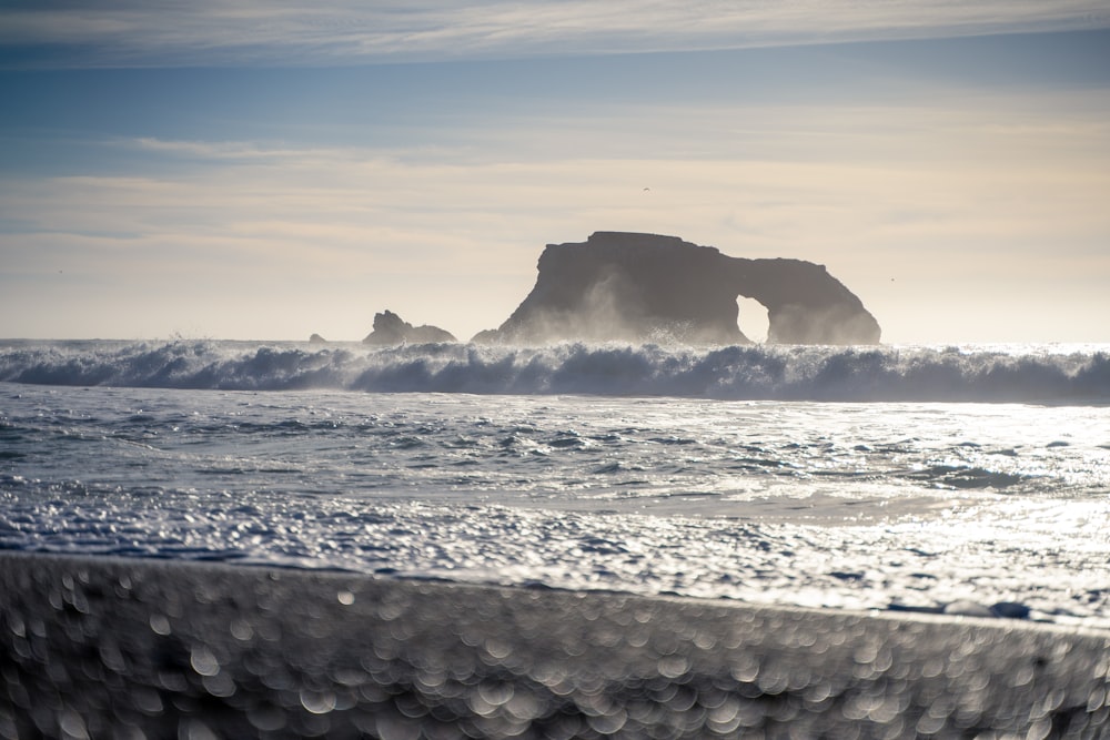 a large body of water with a rock in the background