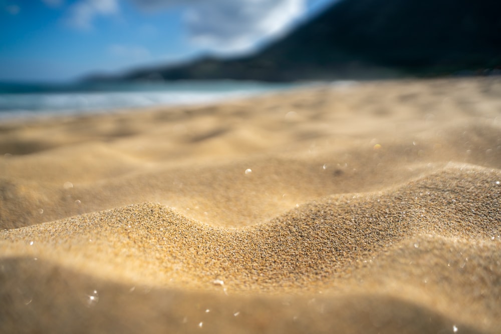 a close up of sand on a beach with a mountain in the background