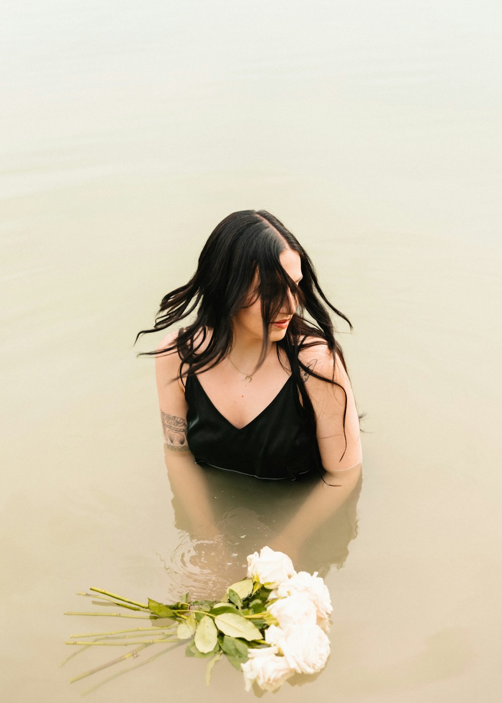 a woman in a body of water with a bouquet of flowers