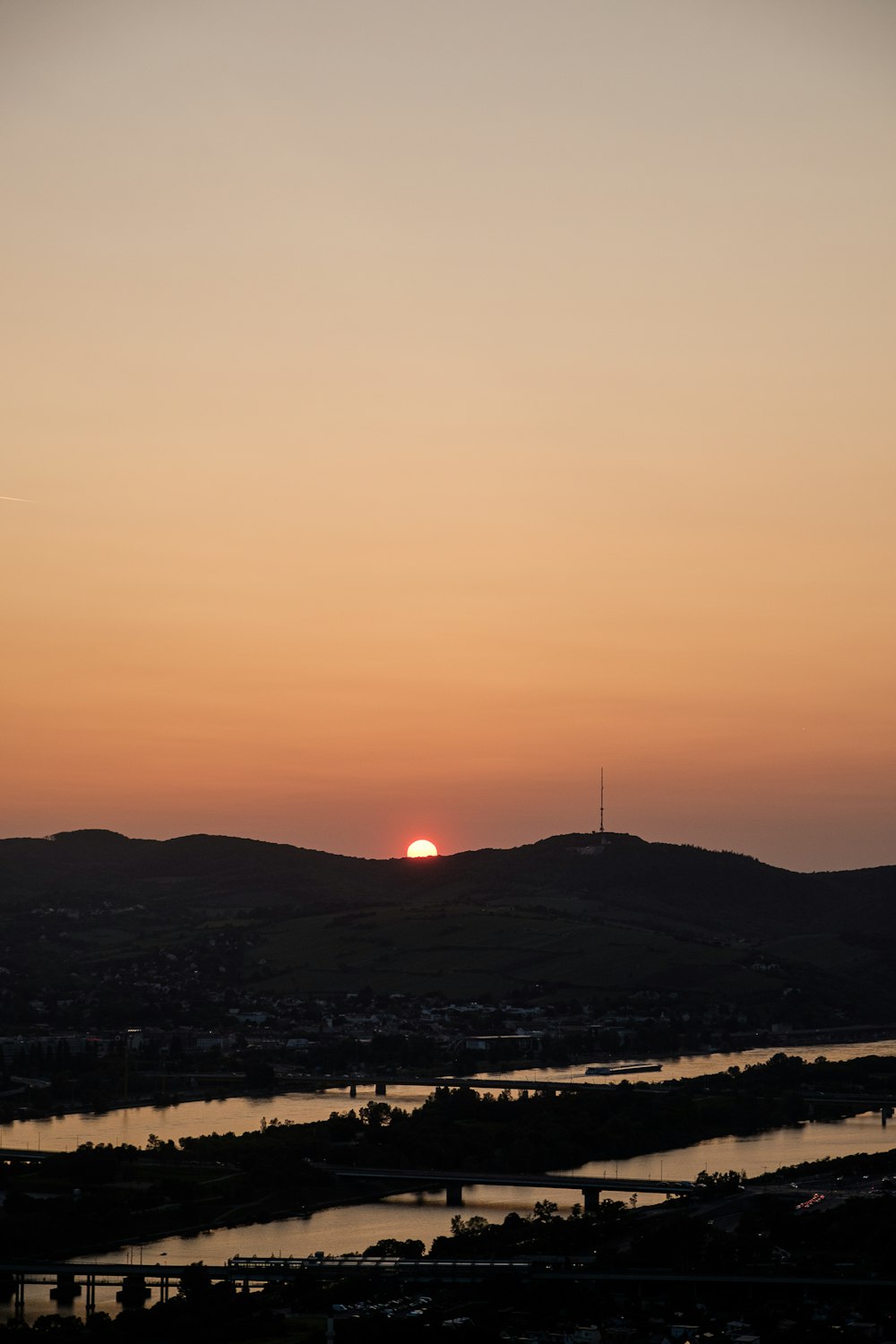 the sun is setting over a river and hills