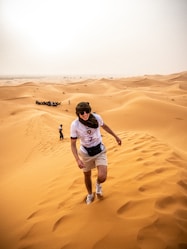 a man walking across a sandy field