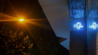 A vibrant neon box sign glowing warmly outside a cozy Surabaya coffee shop at dusk