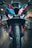 A close-up view of a high-performance motorcycle featuring an aggressive front design with sharp headlights and a colorful body with black, blue, red, and orange details. The image captures the bike's front tire, aerodynamic components, and a part of the showroom in the background.