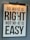 A framed motivational poster with the phrase 'Do what is right, not what is easy' written in large, bold black lettering on a white background. A light fixture is positioned above the frame, casting a warm glow. Reflections of a window or similar structures are visible on the surface of the glass.