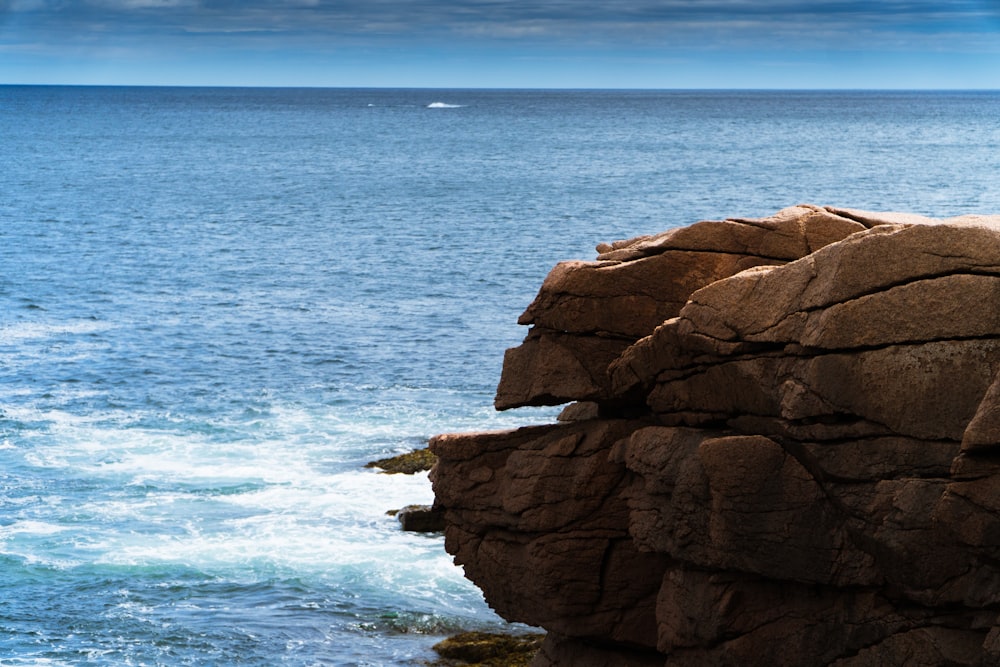 a man standing on top of a cliff next to the ocean