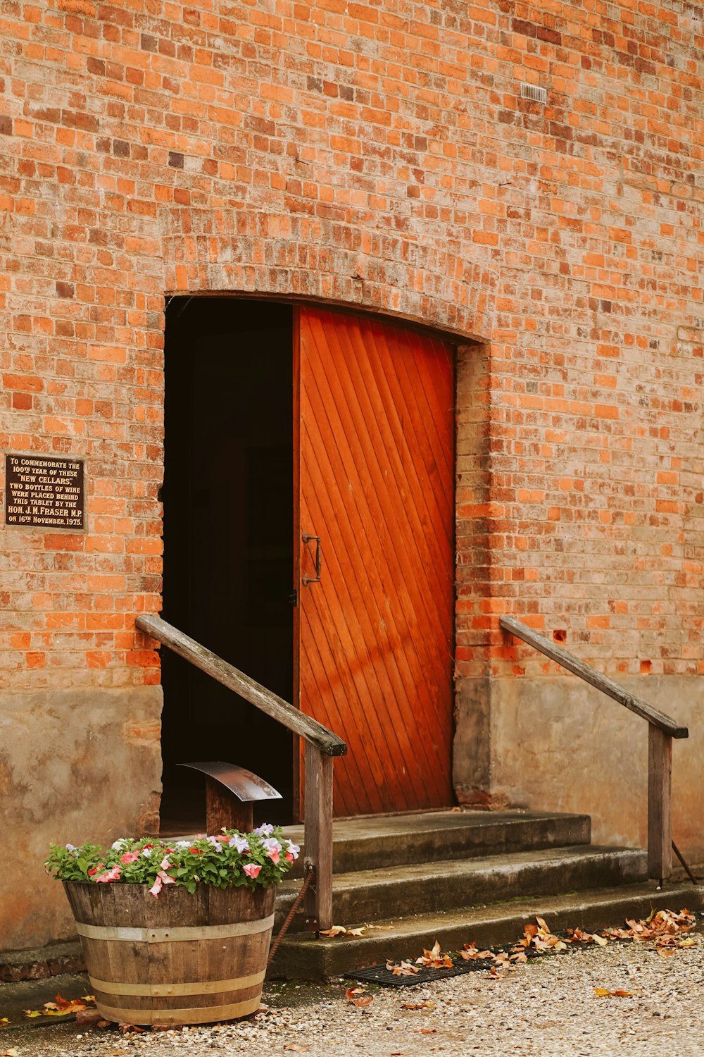a brick building with a red door and a planter with flowers
