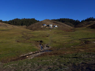 Open land with a small stream running through and hills in the background.
