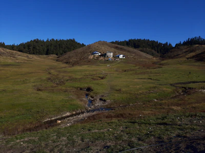 Open land with a small stream running through and hills in the background.