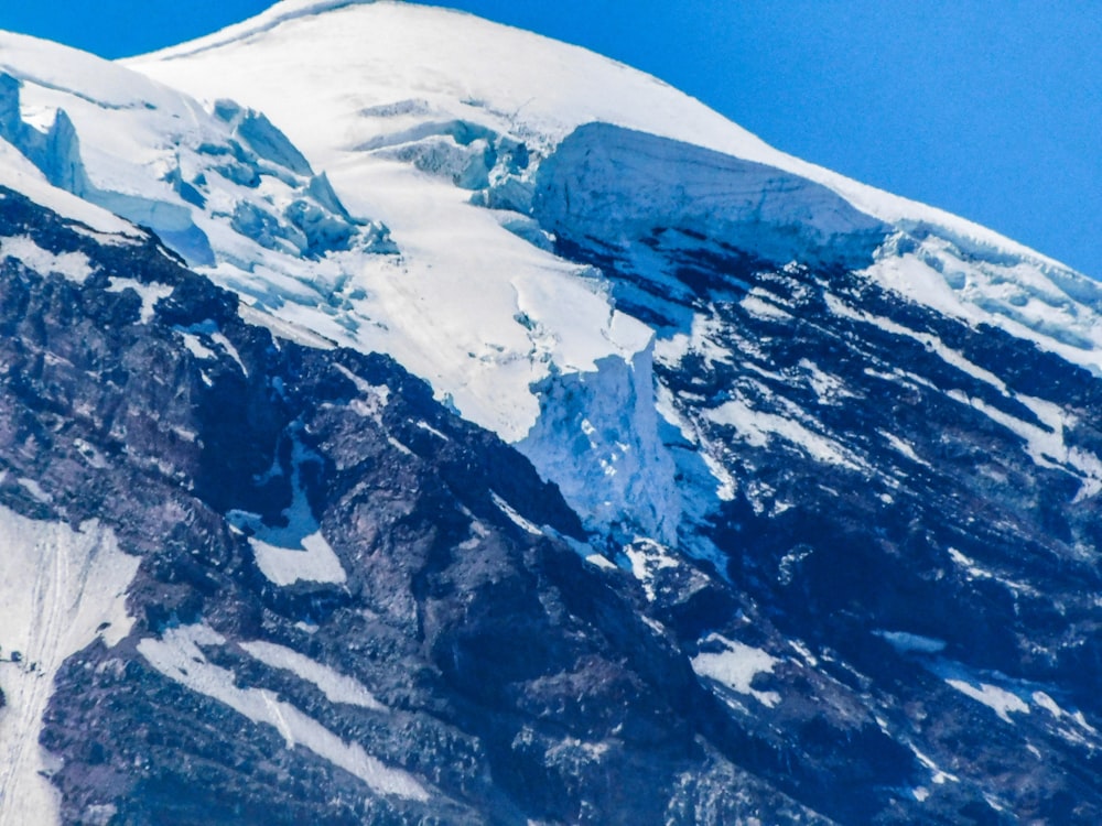 a large mountain covered in snow under a blue sky