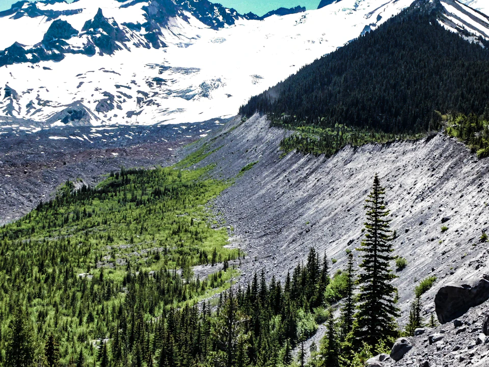 Mountain range with snow-capped peaks and lush green valley below in clear blue sky