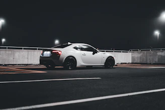 Futuristic roadster with minimalist design parked on an empty highway at night.