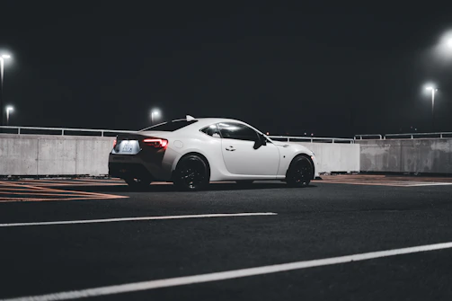 Futuristic roadster with minimalist design parked on an empty highway at night.