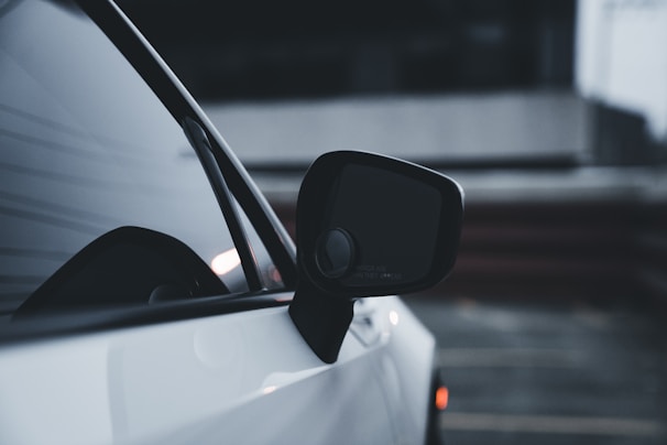 Close-up of a gloved hand polishing the side mirror of a sleek black sedan.