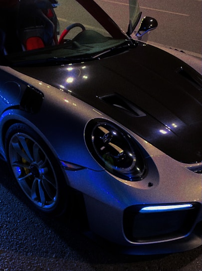 Sleek Corvette C8 with a subtle carbon fiber hood reflecting ambient city lights at night.