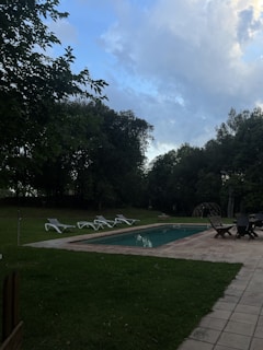 A serene backyard with a pool and lounge chairs under the sun.