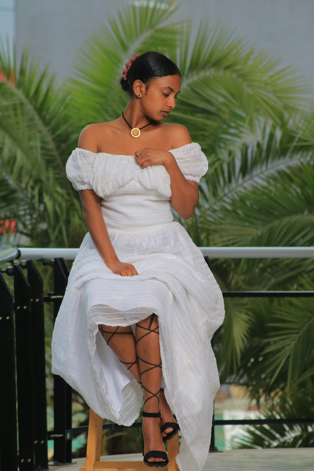 a woman in a white dress sitting on a stool