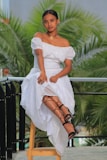 a woman in a white dress sitting on a stool