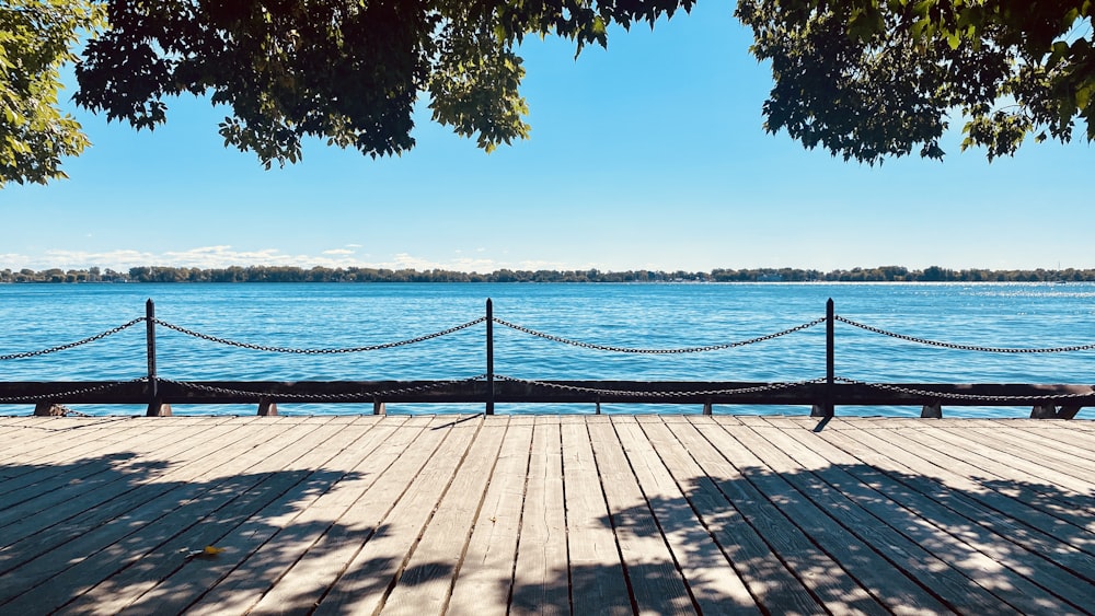 a bench sitting on top of a wooden pier next to a body of water