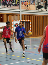 A dynamic basketball game in progress with players focused and energetic on an indoor court.