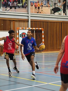 Close-up shot of basketball players in bold red and black jerseys, mid-game with intense focus.
