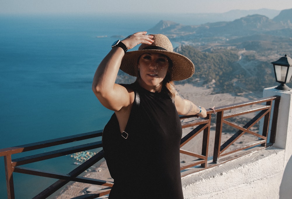 a woman in a hat standing on a balcony