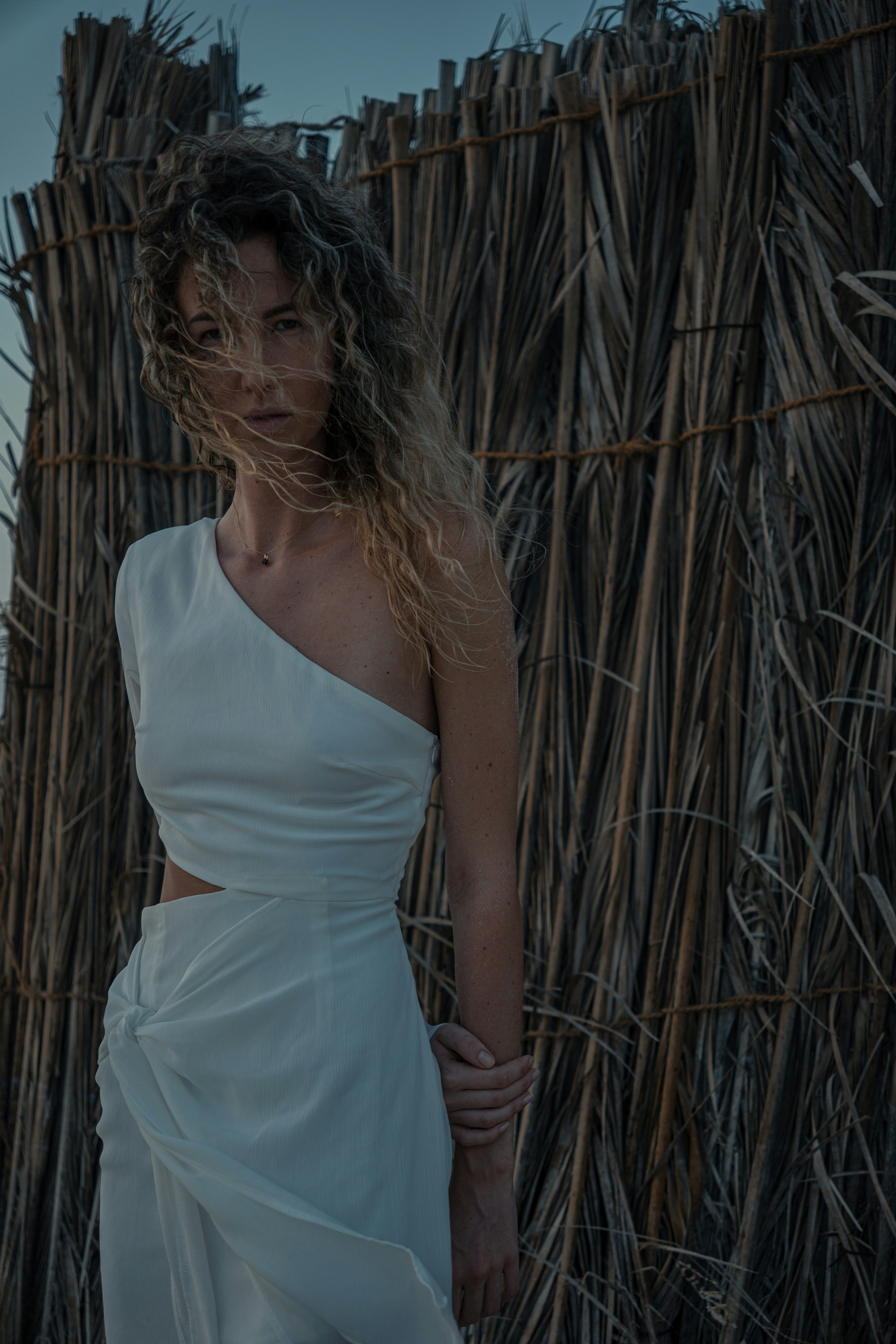 a woman in a white dress standing in front of a fence