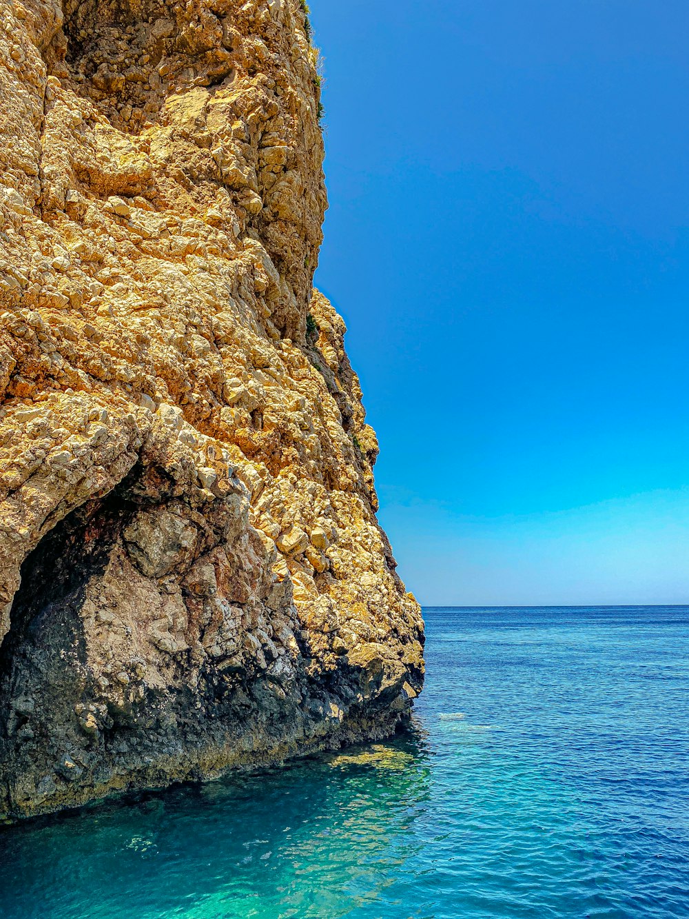 a rocky cliff with a body of water in front of it