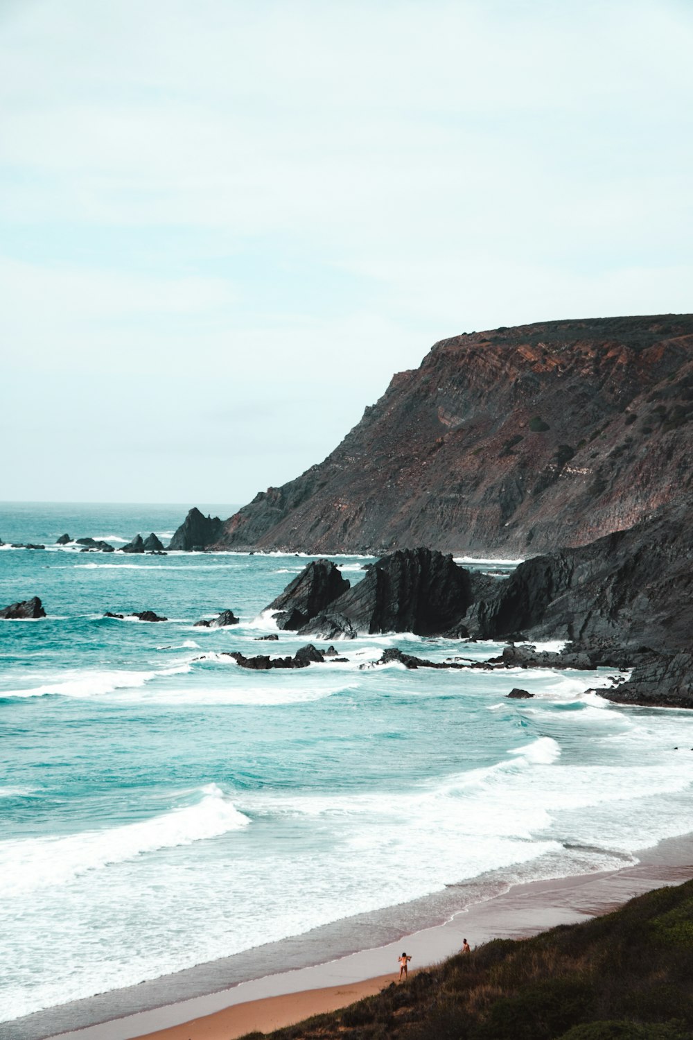 a sandy beach next to a rocky cliff