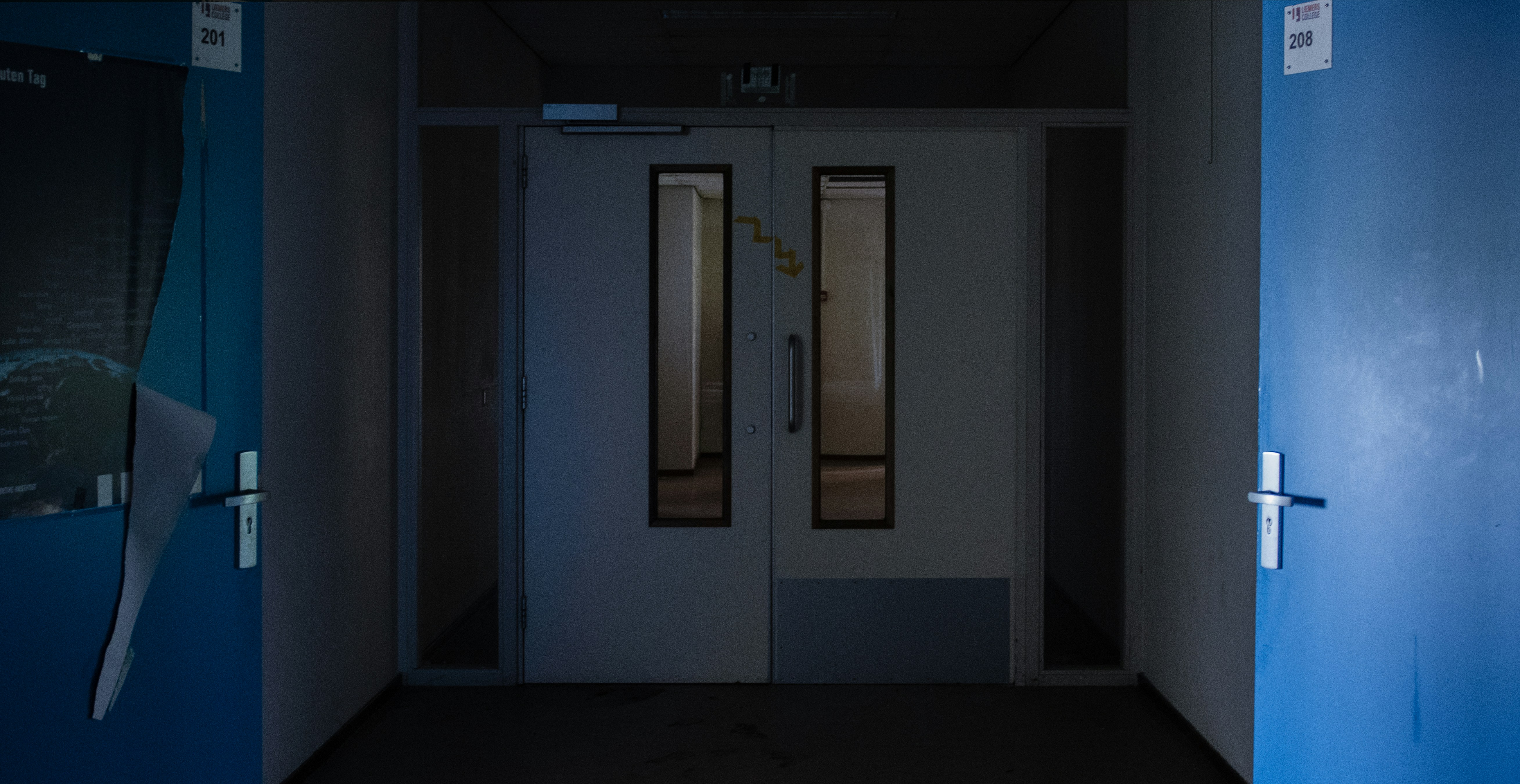 青いドアと白い壁の暗い廊下