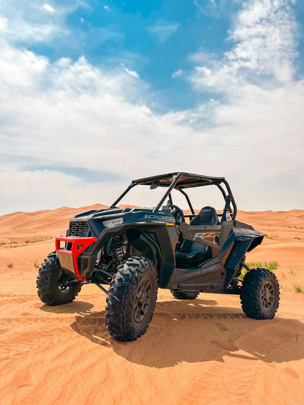 a four - wheeled vehicle driving through the desert on a sunny day