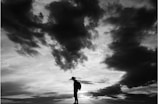 A silhouette of a lone figure standing against a stormy sky.