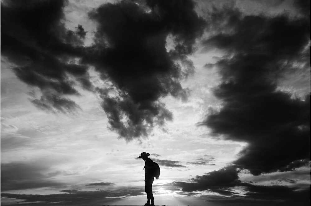 a man standing on top of a hill under a cloudy sky